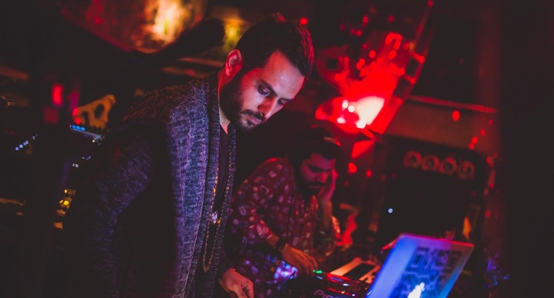 Heimat performing behind the decks in a red-lit nightclub